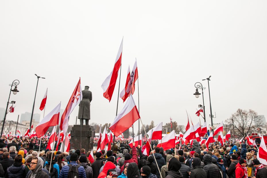 zdjęcie przedstawia tłum ludzi zgromadzonych wokół pomnika marszałka Piłsudskiego trzymających w rękach flagi Polski