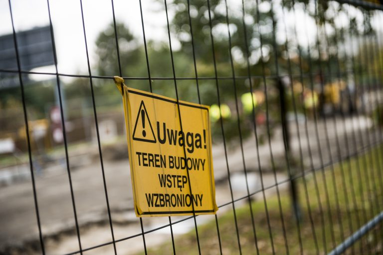 zdjęcie przedstawia ogrodzenie z siatki na którym zawieszony został znak Uwaga! Teren budowy, wstęp wzbroniony