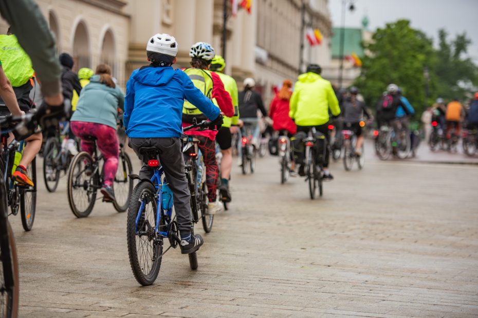 Zdjęcie przedstawia dużą grupę cyklistów na różnego rodzaju rowerach poruszającą się w kolumnie, w okolicy placu Zamkowego