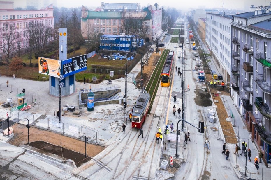 Zdjęcie przedstawia skrzyżowanie alei Niepodległości z ulicą Rakowiecką z lotu ptaka. Widoczne jest nowe torowisko tramwajowe. Na szynach stoją dwa tramwaje. Po lewej stronie widać budynki SGH.