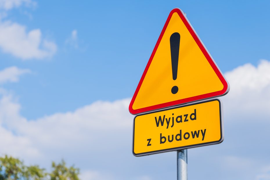 Znak drogowy uwaga, pod nim tabliczka wyjazd z budowy