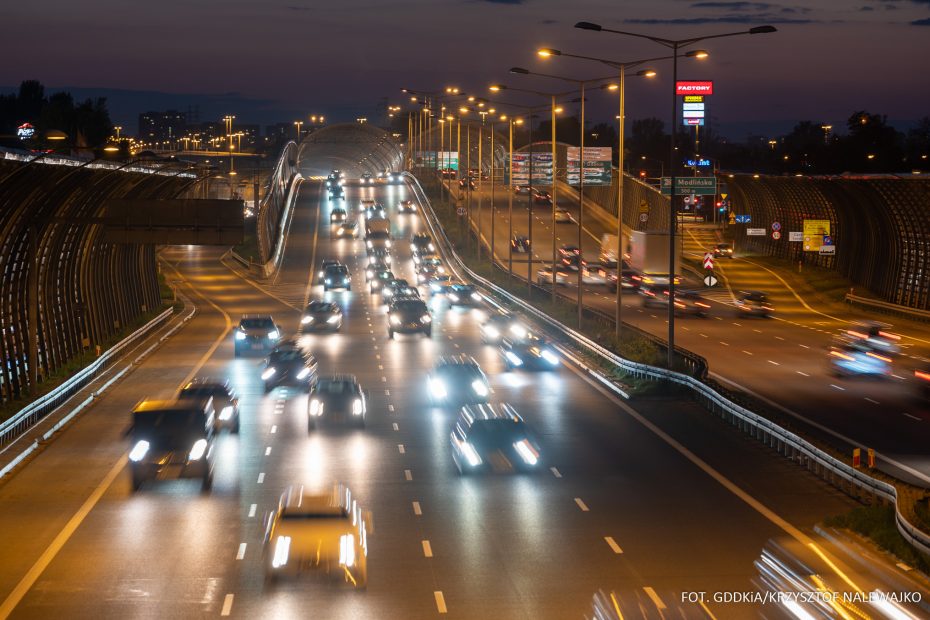 Zdjęcie przedstawia jezdnie główne Trasy S-8 nocą. Wszystkimi ośmioma pasami obu nitek drogi ekspresowej poruszają się samochody. Fotografia przedstawia okolice Węzła Łopuszańska.