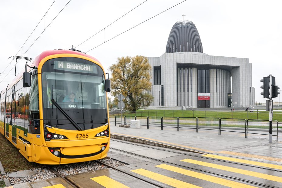 Zdjęcie przedstawia tramwaj stojący na przystanku w Alei Rzeczypospolitej. W tle widać Świątynię Opatrzności Bożej.